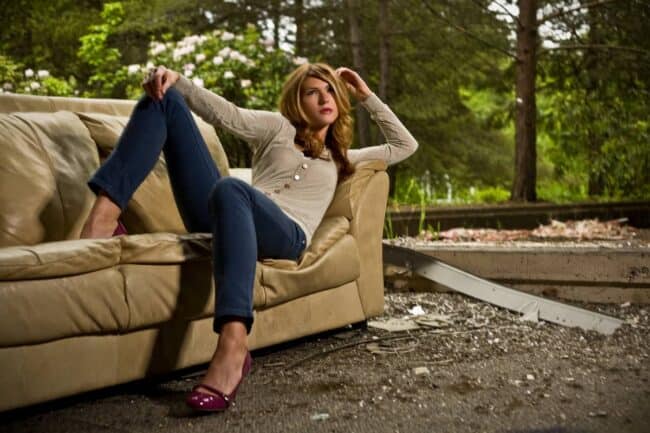 Woman relaxing on a couch outdoors amid construction debris