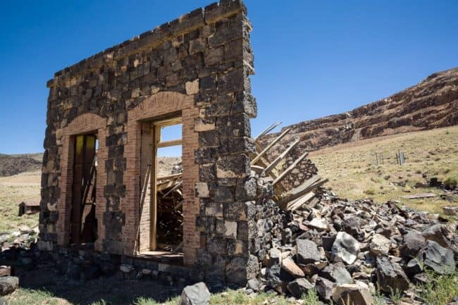 Stone ruins of an abandoned building in the ghost town of Luning, Nevada under a clear blue sky