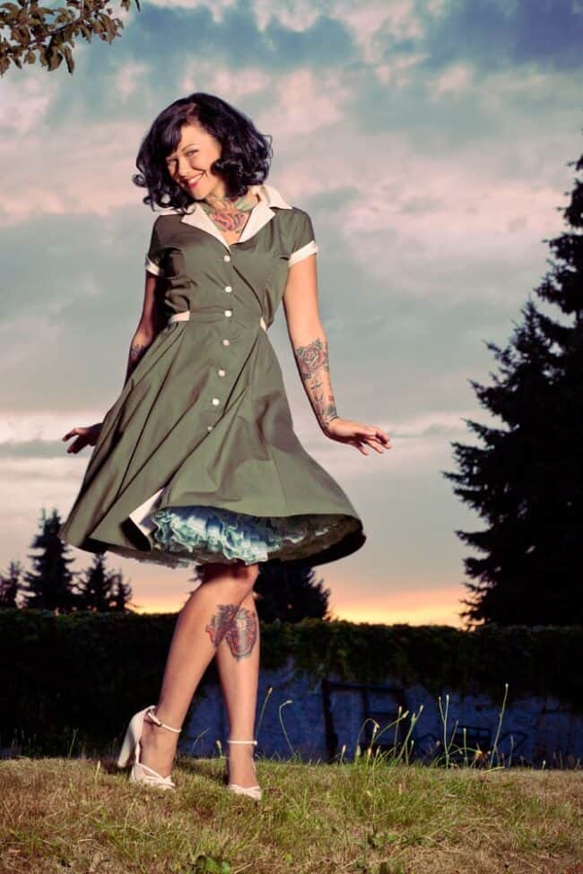 Woman in a vintage green dress twirling outdoors at dusk