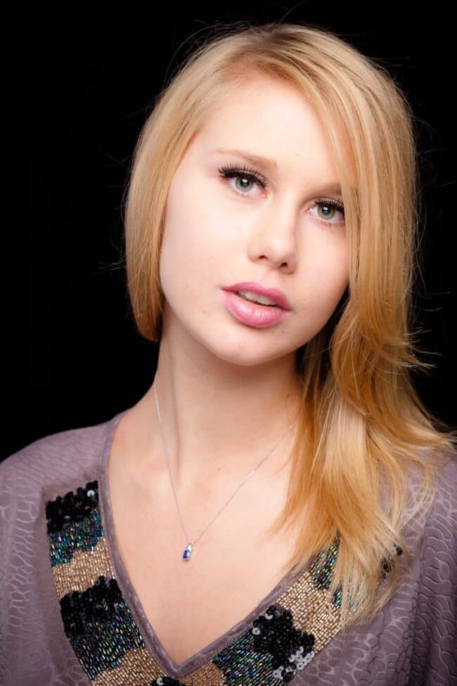 Studio headshot of a blonde woman in a sequined top