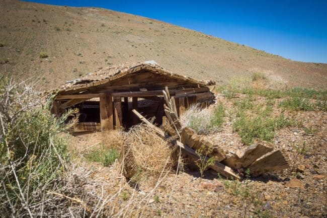 Collapsed wooden structure in a desert landscape under a blue sky