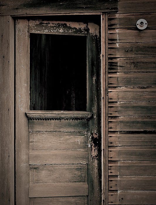 Weathered wooden door of an abandoned building, sepia toned
