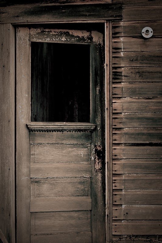 Weathered wooden door of an abandoned building, sepia toned