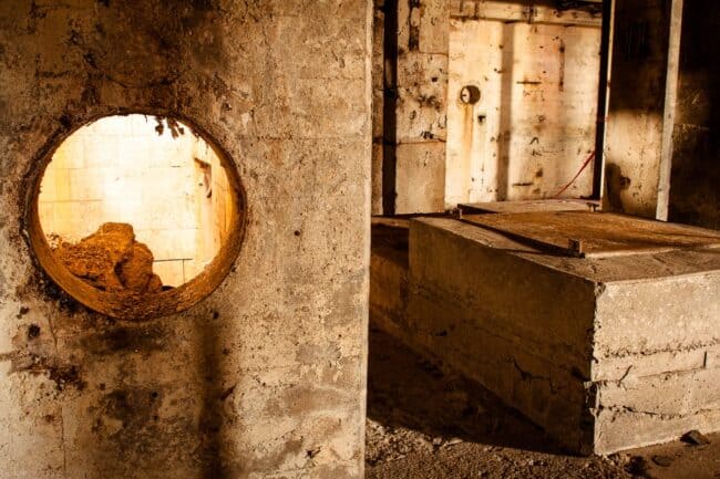 Abandoned industrial interior with a round portal window and concrete vault platform, sepia toned