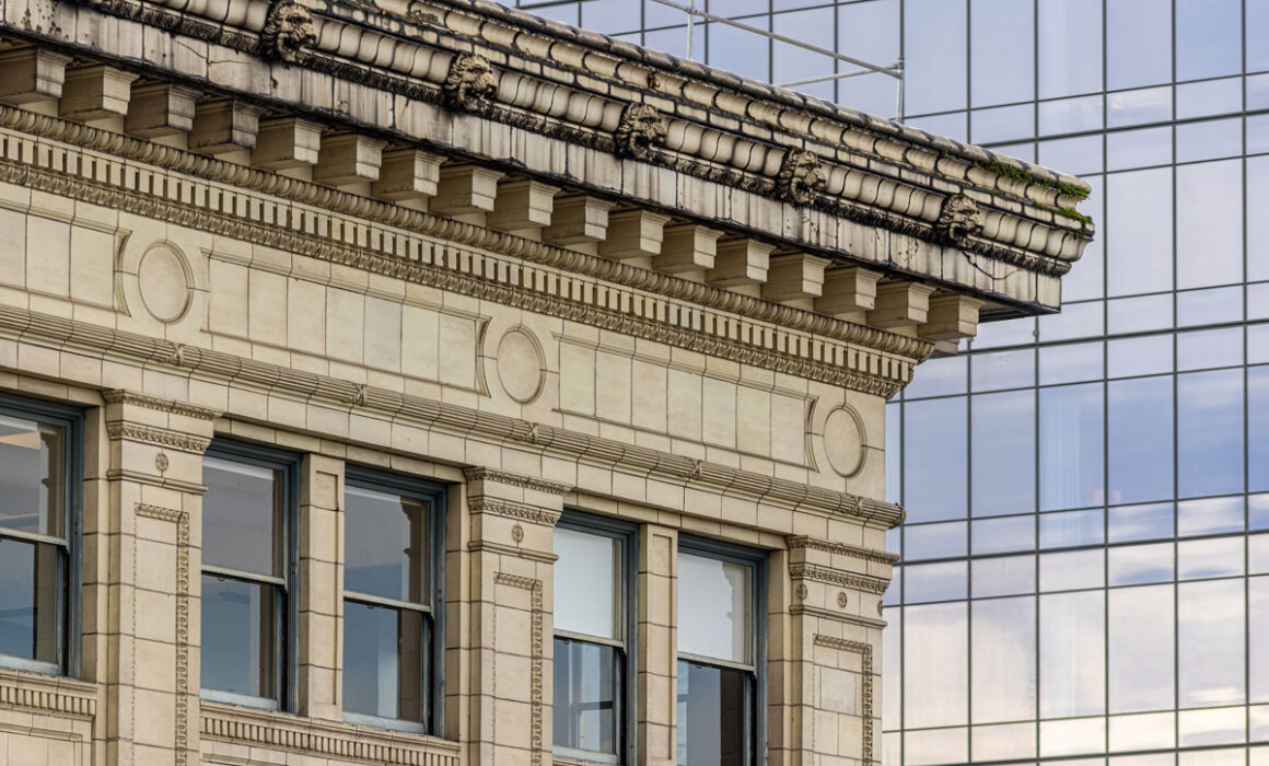 Ornate stone building cornice contrasted against a modern glass skyscraper