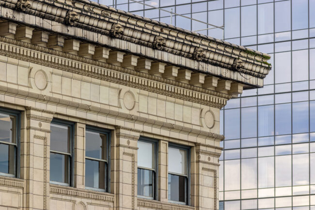Ornate stone building cornice contrasted against a modern glass skyscraper