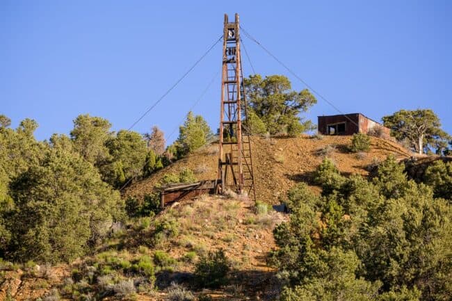 Old wooden mine tram tower on a hillside surrounded by trees