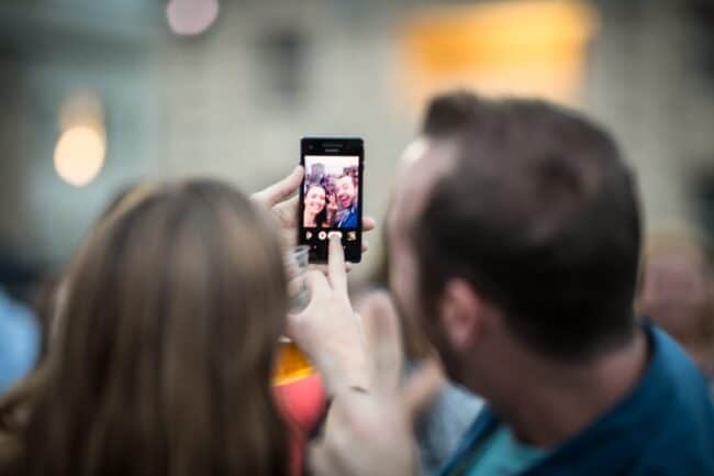 Couple taking a selfie together with a smartphone in a crowd
