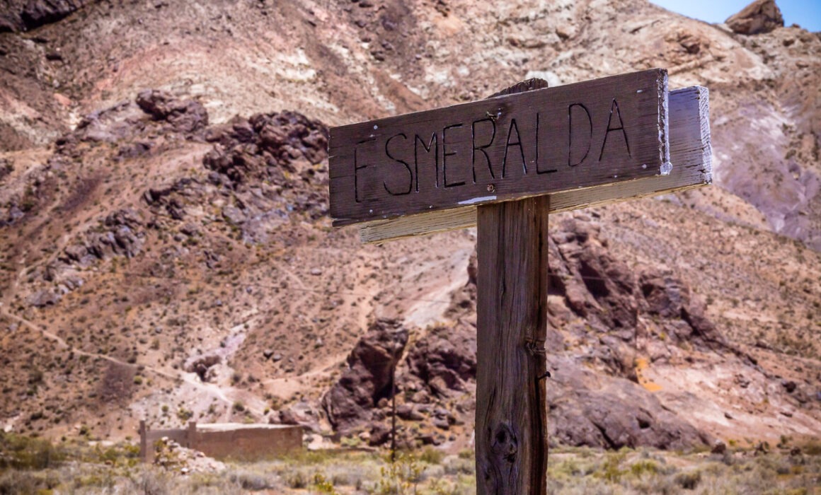 A weathered sign in the Nevada desert reading "Esmeralda" in faded lettering
