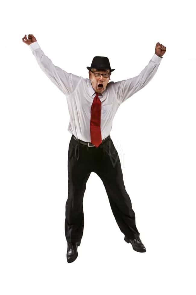 Man in a fedora and tie jumping mid-air with arms raised against a white backdrop
