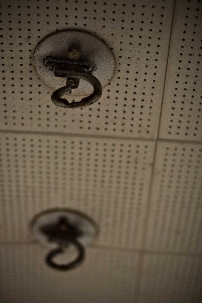 Close-up of vintage ceiling tile with metal hook fixtures under warm amber lighting