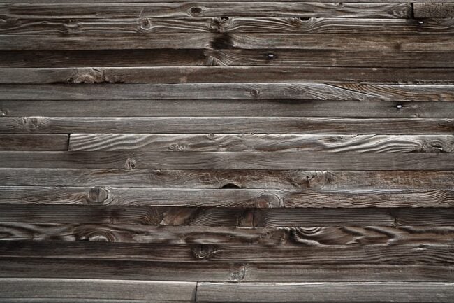 A close-up of weathered gray wooden barn siding boards