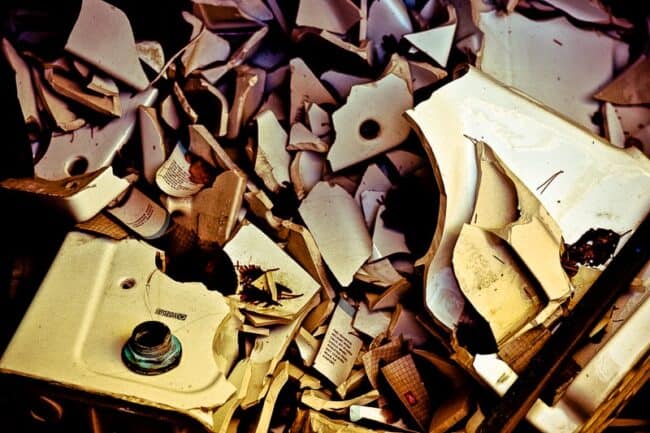 A pile of broken porcelain bathroom fixtures shattered and scattered together, in warm sepia-toned lighting
