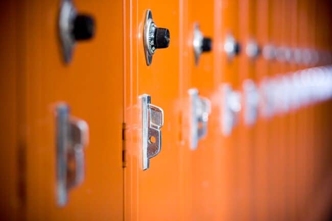 A row of orange school lockers with combination locks, shot with shallow depth of field