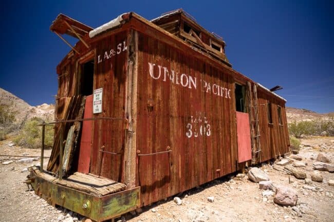 A weathered red wooden Union Pacific railroad caboose sitting in the desert