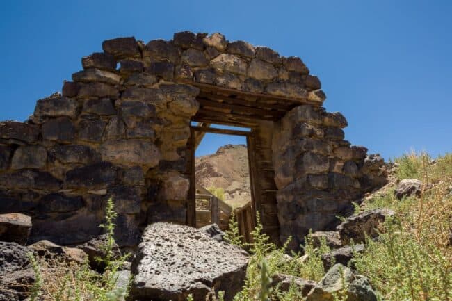 A stone archway doorway in a ruined desert building, framed against a blue sky