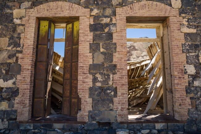 Twin arched brick doorways in a collapsed stone ruin, framing rubble and open sky