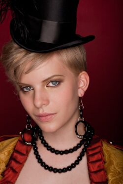 Portrait of a woman in a circus ringmaster costume with a top hat and black beaded jewelry