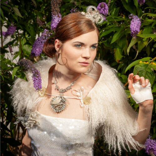 Three-panel triptych of a woman in a white lace dress and jeweled tiara-style headpiece, posed among purple flowering shrubs