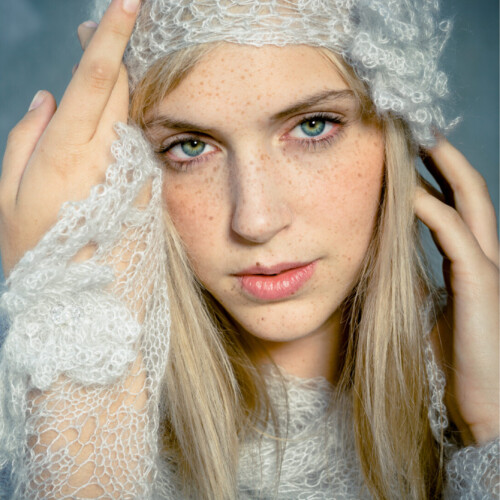 Three-panel close-up triptych of a blonde woman in a white lace headpiece, moody blue-toned lighting